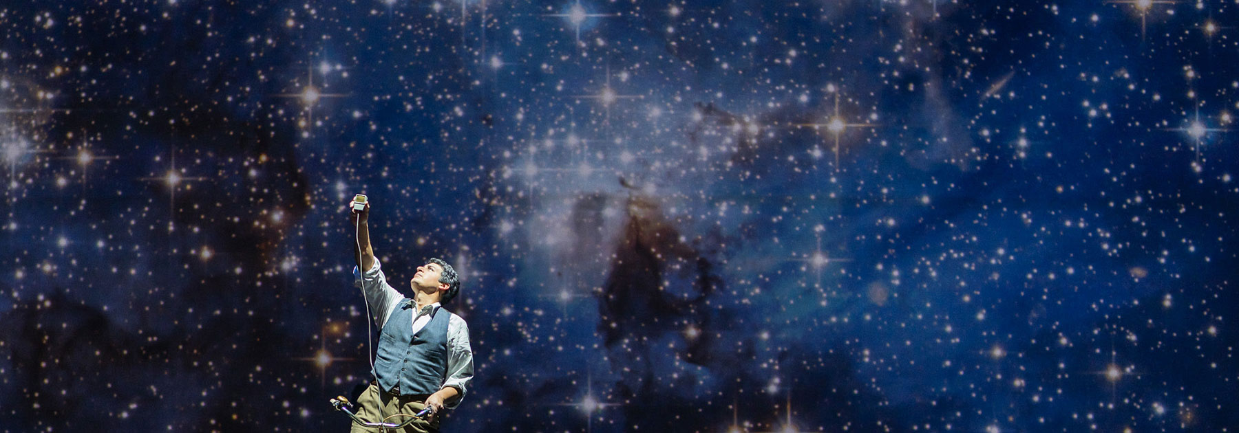 Performer on stage in front of a blue, starry backdrop